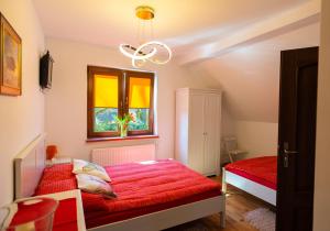 1 dormitorio con cama roja y ventana en DOM POD DĘBAMI, en Gryżyna