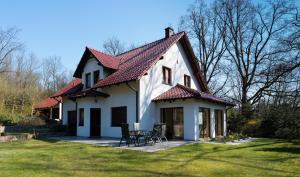 una casa blanca con techo rojo y algunas sillas en DOM POD DĘBAMI, en Gryżyna