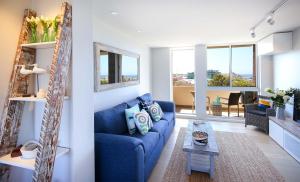 a living room with a blue couch and a table at Bondi Aqua Vista - Walk to beach and shops in Sydney