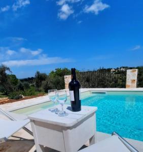 - une bouteille de vin assise sur une table à côté de la piscine dans l'établissement TRULLO PIETRAPOESIA, à Ostuni