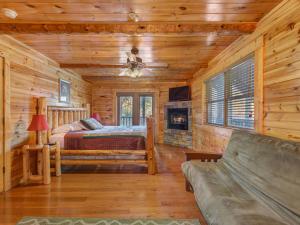 Dormitorio en cabaña de madera con cama y sofá en Family Ties Lodge, en Gatlinburg