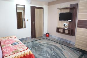 a room with a bed and a flat screen tv at STAYMAKER Hotel Suraj - Only Indian Citizens Allowed in Haldia