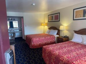 a hotel room with two beds and a bathroom at Holiday Motel Oakdale in Oakdale