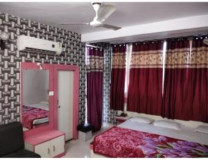 a bedroom with two beds and a mirror and red curtains at Hotel Agrawal, Pachmarhi in Pachmarhī