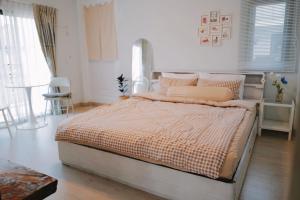 1 dormitorio con 1 cama en una habitación blanca en Nhunjai House - บ้านหนุนใจ, en Chiang Rai