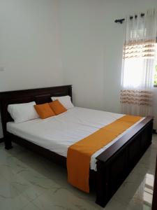 Bett mit orangefarbenen und weißen Kissen in einem Zimmer in der Unterkunft Ashi Galle Villa in Galle