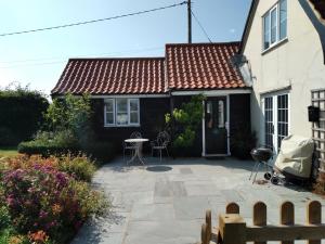 a house with a patio with a table and chairs at Brick Kiln Apartment in Campsey Ash