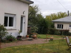 un patio trasero de una casa con un jardín con columpio en Le petit Loir, gîte sur la Loire à vélo, 