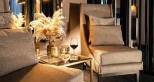 una sala de estar con una silla y una copa de vino en Victor's Residenz-Hotel Gummersbach, en Gummersbach
