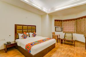 a bedroom with a large bed and a chair at FabHotel Shimla Resort in Lucknow