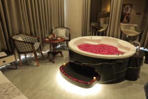 uma grande banheira cheia de flores vermelhas num quarto de hotel em Apricot Motera em Ahmedabad