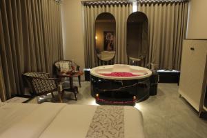 a bedroom with a tub with a mirror and a bed at Apricot Motera in Ahmedabad
