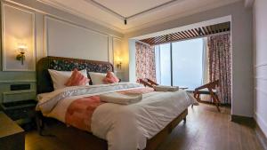 a bedroom with a large bed with a large window at Hotel Sonar Bangla Darjeeling in Darjeeling