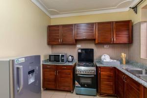 a kitchen with wooden cabinets and stainless steel appliances at Victoria Breeze Suites, Entebbe in Entebbe