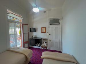 a bedroom with two beds and a tv and a window at Ulmarra Hotel in Ulmarra