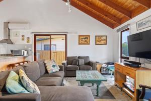 un soggiorno con un divano e una TV di Beilby Beach Cottage a Inverloch