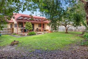 a house with a fence and a yard at Beilby Beach Cottage in Inverloch