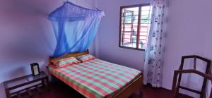 a bedroom with a bed with a blue curtain and a window at Blackstar Inn in Trincomalee