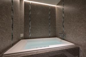 a bath tub in a bathroom with a tile wall at Hotel Pasadena レジャーホテル in Nagoya