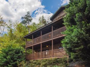 a large building with a deck in the woods at Bear’s Corner, 3 Bedrooms, WiFi, Pool Table, Hot Tub, WiFi, Sleeps 10 in Gatlinburg