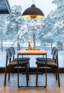 einen Esstisch mit Stühlen und ein großes Fenster in der Unterkunft Wilderness Hotel Juutua in Inari