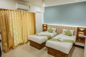 a bedroom with two beds and a window at Hotel Heraa International in Mangalore