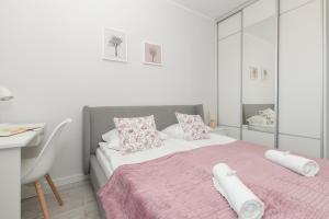 a bedroom with a bed with a pink blanket and a desk at Deluxe Apartments Sucha Gdańsk by Renters in Gdańsk