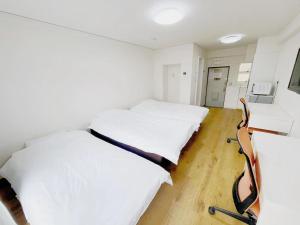 東京にある匯金上板橋ビルの白い壁とウッドフロアの客室で、ベッド2台が備わります。