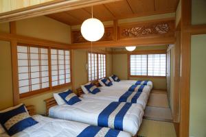 a row of four beds in a room with windows at Living CUBE Beppu in Beppu