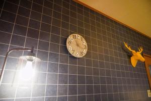 un reloj en una pared de azulejos azules con una luz en Living CUBE Beppu en Beppu