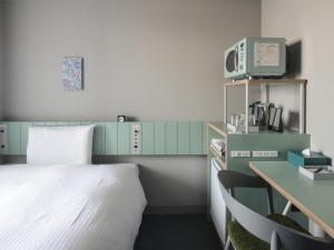 a bedroom with a bed and a desk with a computer at Vessel Inn Takadanobaba Ekimae in Tokyo
