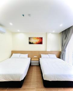 Orion Hotel Halong في ها لونغ: غرفة بسريرين ولوحة على الحائط