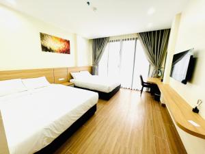 a hotel room with two beds and a desk at Orion Hotel Halong in Ha Long