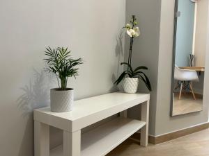 a white bench with two potted plants on it at B&B Radice in Brucoli