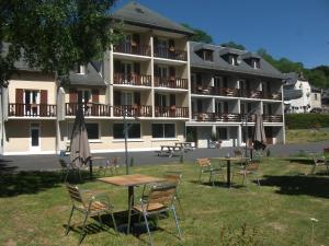 een hotel met tafels en stoelen voor een gebouw bij Le Brunet in Saint-Jacques-des-Blats