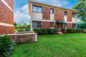 a brick house with a green lawn in front of it at Victoria Breeze Suites, Entebbe in Entebbe