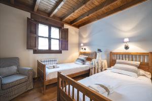a bedroom with two beds and a chair and a window at La Coqueta Del Sueve in Arriondas