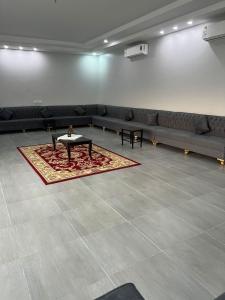 una habitación con sofás, una mesa y una alfombra en شاليه ريفان en Umm Lajj