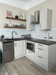 cocina con armarios blancos, fregadero y microondas en Norton house en Brighton & Hove