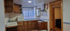 a small kitchen with wooden cabinets and a window at Casarão do Alva in Penalva de Alva