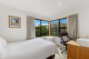 a bedroom with a bed and a desk and a window at Charming house with lovely views in Queenstown