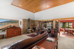 a living room with a leather couch and a piano at Charming house with lovely views in Queenstown