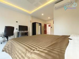 een slaapkamer met een bed, een bureau en een televisie bij TY Holiday Resort in Pattaya
