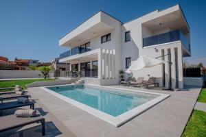 een groot wit huis met een zwembad bij Villa Andris-luxury villa near sandy beach - by TRAVELER tourist agency KRK in Ližnjan