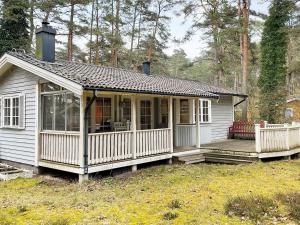 Holiday home YNGSJÖ III في Yngsjö: منزل أبيض صغير مع شرفة على ميدان