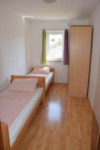 twee bedden in een kleine kamer met een raam bij Apartment Blanusa C in Povljana