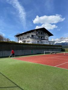 un hombre jugando al tenis en una pista de tenis con un edificio en Haus Central, en Schladming