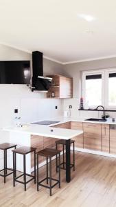 a kitchen with white cabinets and a table and stools at Sterla - Masuria in Giżycko