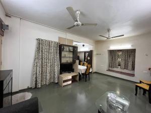 a living room with a ceiling fan and a dining room at Tripvana Apartment in Nashik