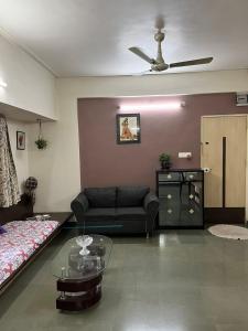 a living room with a couch and a ceiling fan at Tripvana Apartment in Nashik